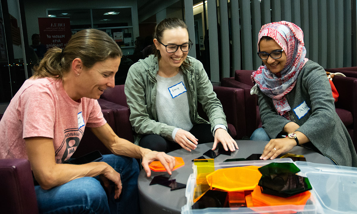 A group of three women sitting down working on a math puzzle at a table
